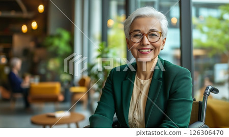 Confident senior woman with a short hairstyle and glasses smiling in a bright, modern space 126306470