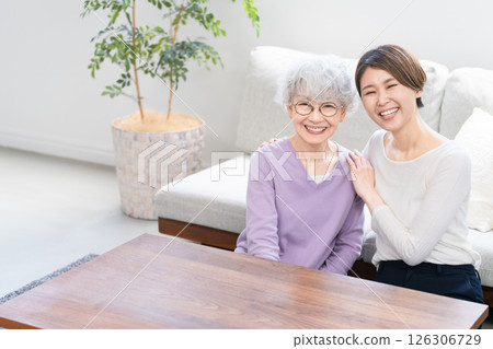 A young woman and a senior woman sitting side by side A young woman and a senior woman sitting side by side 126306729