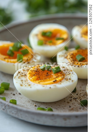 Five soft-boiled egg halves with runny yolks, topped with chopped green onions and black pepper Five soft-boiled egg halves with runny yolks, topped with chopped green onions and black pepper 126307562