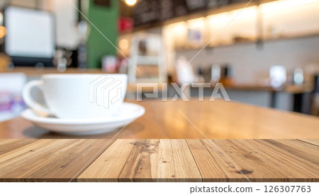 A wooden table in the foreground with a blurred coffee cup and cafe interior in the background. A wooden table in the foreground with a blurred coffee cup and cafe interior in the background. 126307763