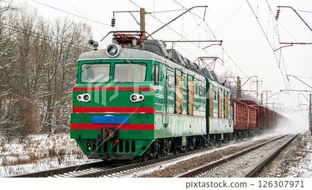 Old Soviet electric locomotive with a heavy freight train in winter in Kyiv Oblast of Ukraine 126307971