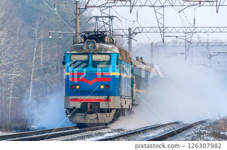 Passenger train rapidly moving along the snowy track 126307982
