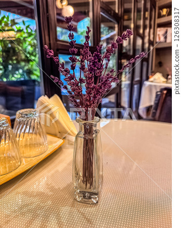 Dried purple flowers arranged in a glass vase on a table with soft background ambiance. High quality photo Dried purple flowers arranged in a glass vase on a table with soft background ambiance. High quality photo 126308317