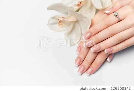 Woman showing french manicure and white orchid flower 126308342