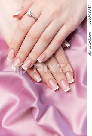 Woman showing french manicure on pink satin background Woman showing french manicure on pink satin background 126308344