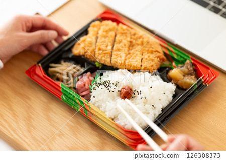 一位中年婦女在辦公桌前吃炸豬排便當 126308373