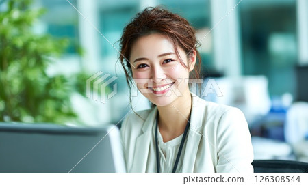 一位微笑的日本女商人在辦公室的電腦前工作 126308544