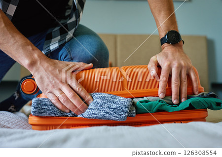 Man packing suitcase with clothes, preparing for travel Man packing suitcase with clothes, preparing for travel 126308554
