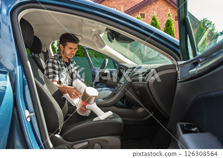 Man cleaning car dashboard with handheld vacuum cleaner Man cleaning car dashboard with handheld vacuum cleaner 126308564