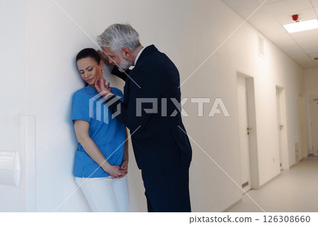 Hospital manager harassing attractive nurse in healthcare setting. Hospital manager harassing attractive nurse in healthcare setting. 126308660