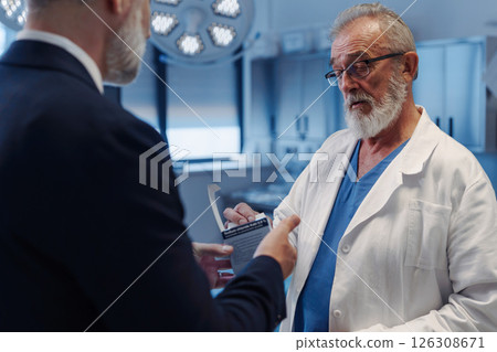 Medical sales representative introducing pharmaceutical products to doctor. Hospital setting. 126308671