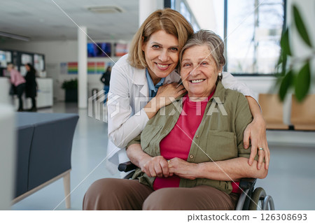 Elderly patient in wheelchair and female physician smiling at clinic. 126308693