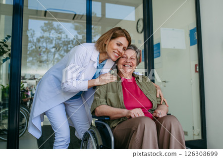 Elderly patient in wheelchair and female physician smiling at clinic. 126308699