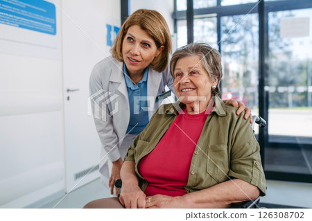Elderly patient in wheelchair and female physician smiling at clinic. 126308702