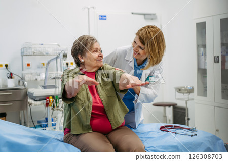 Geriatrician examining senior woman's mobility during routine check-up, 126308703