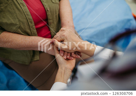 Doctor holding hands with senior patient in compassionate gesture. 126308706