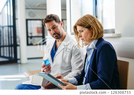 Female medical sales representative presenting medication to doctor Female medical sales representative presenting medication to doctor 126308733