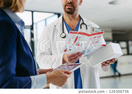Female medical sales representative introducing pharmaceutical products to doctor. Female medical sales representative introducing pharmaceutical products to doctor. 126308736