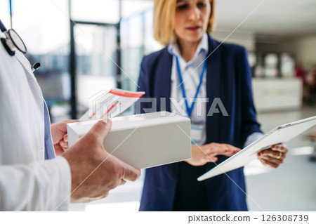 Female medical sales representative presenting medication to doctor 126308739