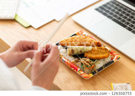 一位中年婦女在辦公室的辦公桌上吃著海苔便當 一位中年婦女在辦公室的辦公桌上吃著海苔便當 126308755