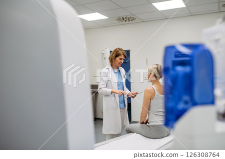 Doctor explaining results from CT scan to patient in diagnostic imaging room 126308764