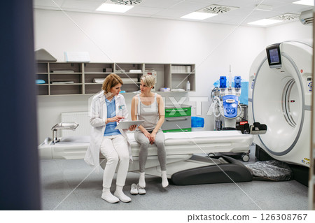 Doctor explaining results from CT scan to patient in diagnostic imaging room 126308767