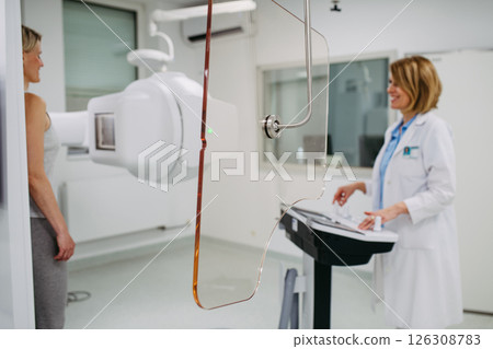 Female patient undergoing dynamic X-ray scan using tilting fluoroscopy wall unit. Female patient undergoing dynamic X-ray scan using tilting fluoroscopy wall unit. 126308783