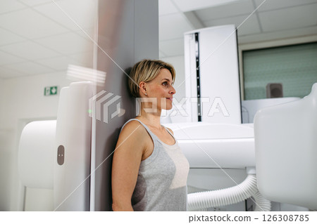 Female patient undergoing dynamic X-ray scan using tilting fluoroscopy wall unit. 126308785