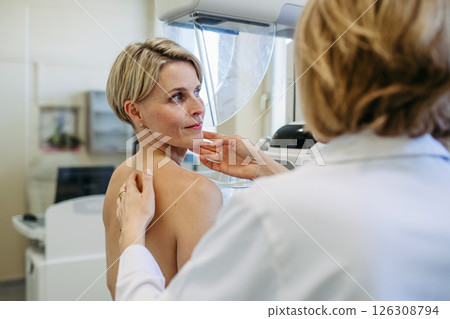 Healthcare professional adjusts the patient for accurate breast imaging. Healthcare professional adjusts the patient for accurate breast imaging. 126308794