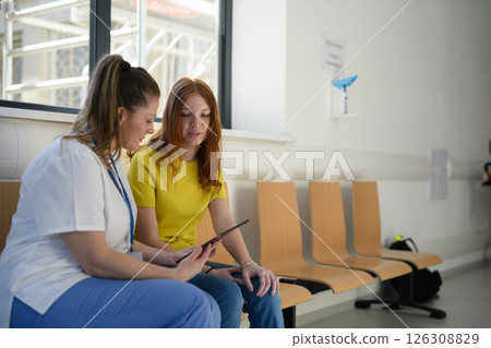 Nurse talking with teenage patient in hospital waiting room. 126308829