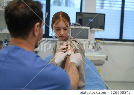 Vaccination of teenage girl during routine health checkup at hospital. Vaccination of teenage girl during routine health checkup at hospital. 126308842