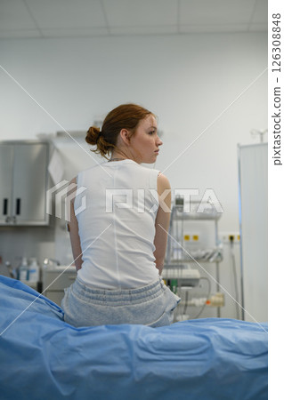 Rear view of teenage girl waiting for medical examination in hospital. 126308848