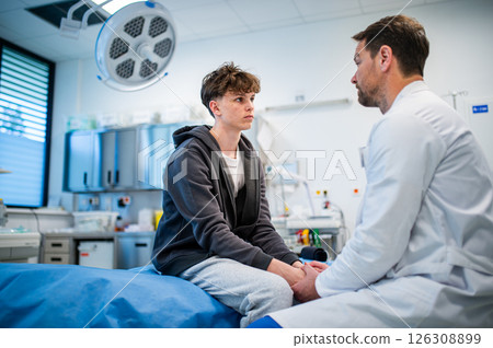 Depressed teenage patient sitting on hospital bed, talking with caring doctor. Depressed teenage patient sitting on hospital bed, talking with caring doctor. 126308899