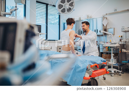 Teen boy undergoing medical checkup with doctor in hospital room. 126308908