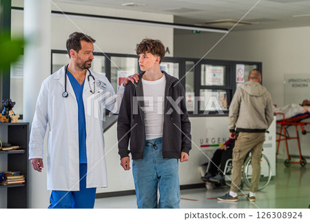 Doctor walking with teenage patient after successful medical procedure in hospital. 126308924