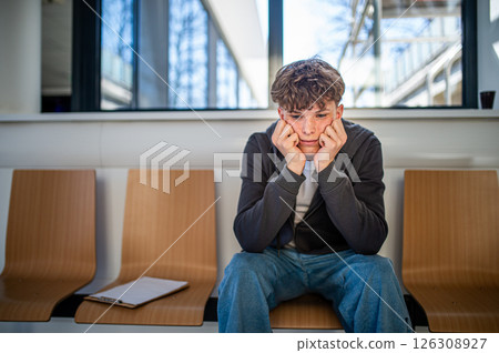 Teenage boy waiting alone in hospital waiting area before medical checkup. 126308927