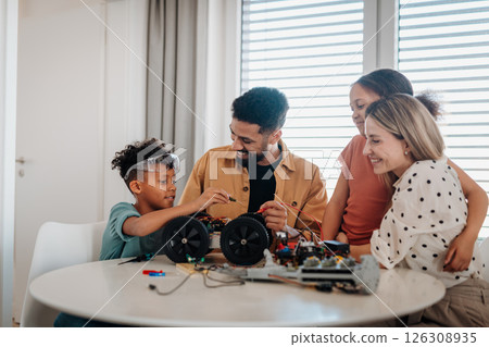 Parents encouraging children to explore robotics and technical skills. 126308935