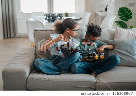 Siblings building robotic car at home as part of STEM learning. Siblings building robotic car at home as part of STEM learning. 126308967