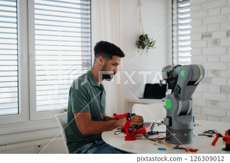 Side view of engineer building and programming a robotic arm at home. 126309012