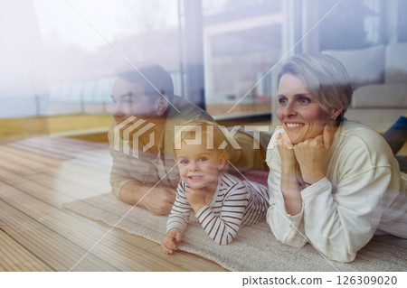 Parents looking out of window with little son, lying on floor. Parents looking out of window with little son, lying on floor. 126309020