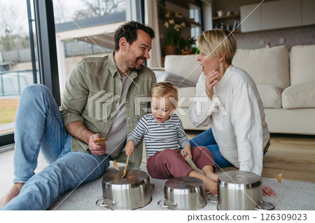 Parents and toddler son playing drums on kitchen pots 126309023