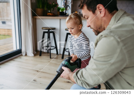 Little boy and dad vacuuming floors with a vacuum cleaner. 126309043