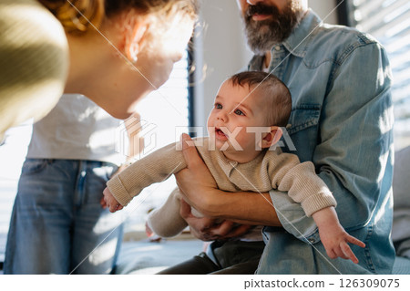 Older sister looking at newborn brother in fathers arms. 126309075