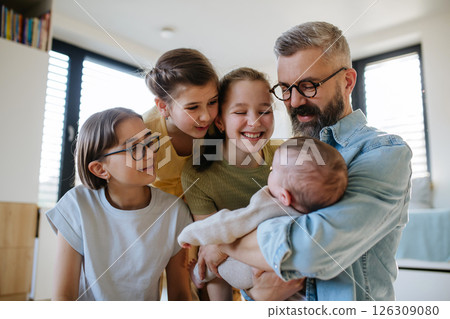 Three sisters looking at newborn brother in fathers arms. Three sisters looking at newborn brother in fathers arms. 126309080
