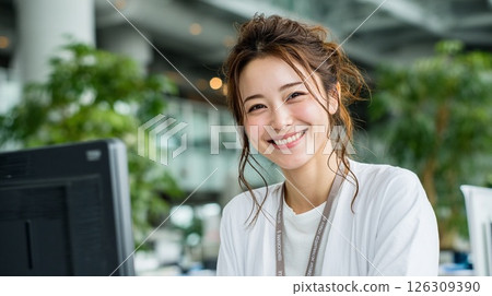 Smiling young Japanese woman working at a computer in an office 126309390