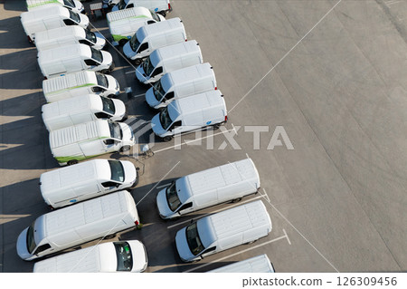 Rows of white electric delivery vans at charging stations for electric vehicles Rows of white electric delivery vans at charging stations for electric vehicles 126309456