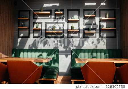 Modern cozy cafe interior with sunlight casting plant shadows on the wall. 126309560
