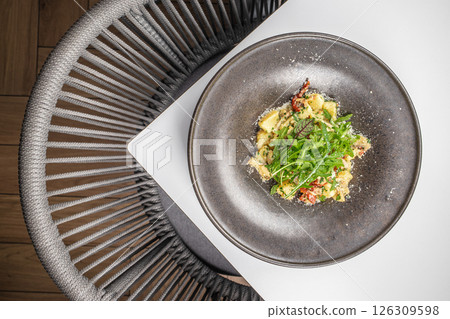 Delicious gnocchi pasta with arugula and sun-dried tomatoes served on a rustic plate 126309598