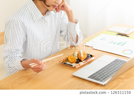 A middle-aged woman suffering from loss of appetite in front of a seaweed lunch box at her desk in the office A middle-aged woman suffering from loss of appetite in front of a seaweed lunch box at her desk in the office 126311150