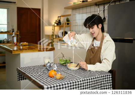 Young asian man enjoying healthy breakfast at home Young asian man enjoying healthy breakfast at home 126311836